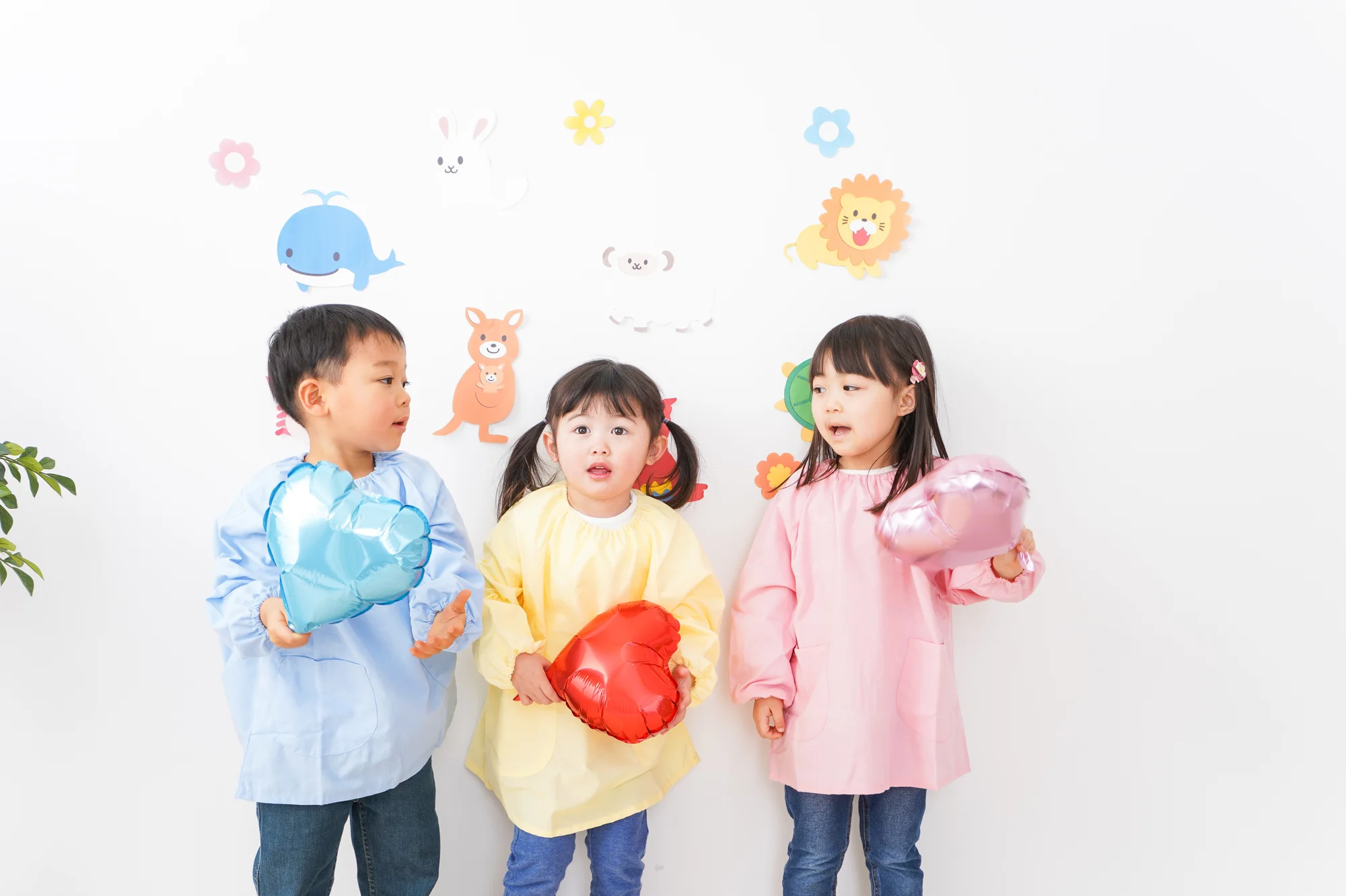 制服を着て風船を持つ3人の園児
